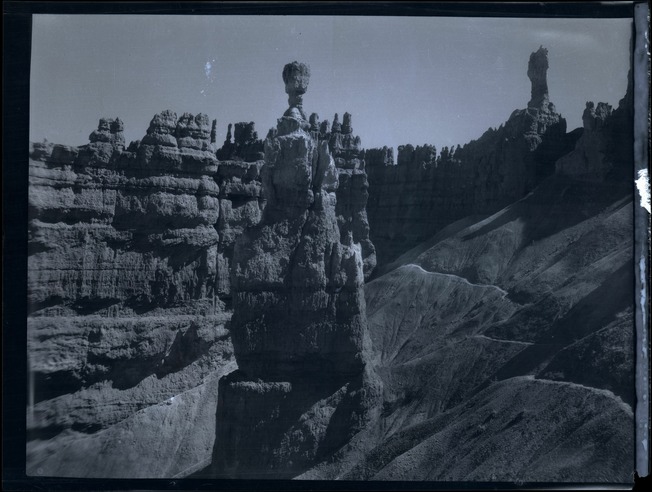 Historic photograph of Thor’s Hammer above a winding trail, with the dark edge of the scanned negative visible.